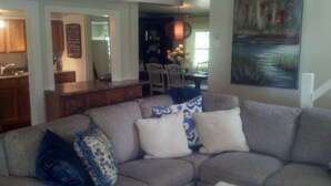 A living room with a gray sectional sofa, a coffee table, and a painting on the wall. - Charming Lake Cottage est 1903! Private and relaxing waterfront, family fun! (Rindge)