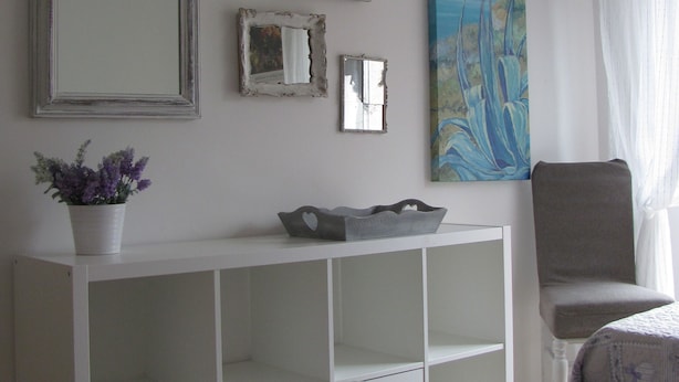 A bedroom with a bed, a white console table with a potted plant, a chair, and three framed mirrors on the wall. - Ideal starting point for visiting Portofino, Riviera, Genoa, Cinque Terre (Rapallo)