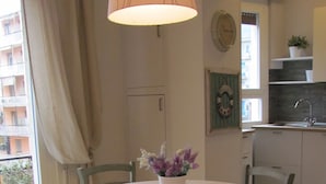 A dining area with a round table, four chairs, a vase with flowers, a hanging lamp, and a view of a balcony with plants. - Ideal starting point for visiting Portofino, Riviera, Genoa, Cinque Terre (Rapallo)