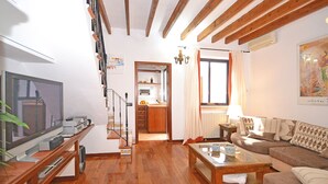 Una sala de estar con una escalera de madera, un televisor, un sofá y una mesa de centro.
