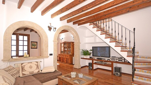 Una sala de estar con escalera de madera, un sofá, una mesa de centro y un televisor.