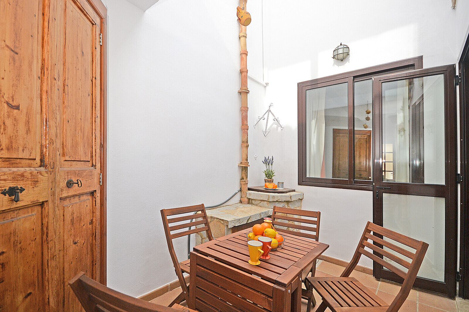 A wooden dining table with chairs, a potted plant, and a window with curtains.