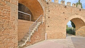 Un arco de piedra que da acceso a una escalera con barandillas de metal.