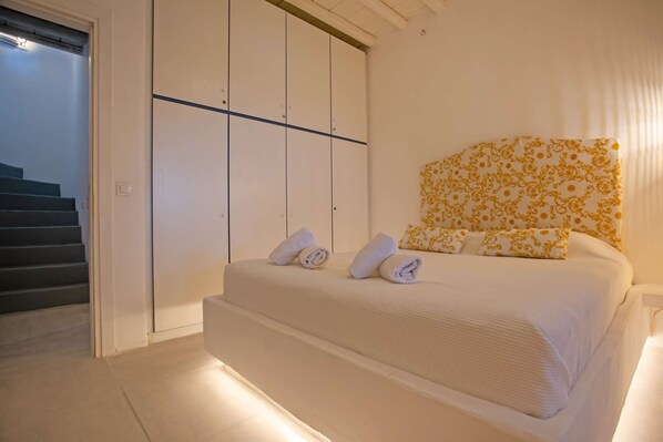 A bedroom with a bed, a wardrobe, and a staircase.