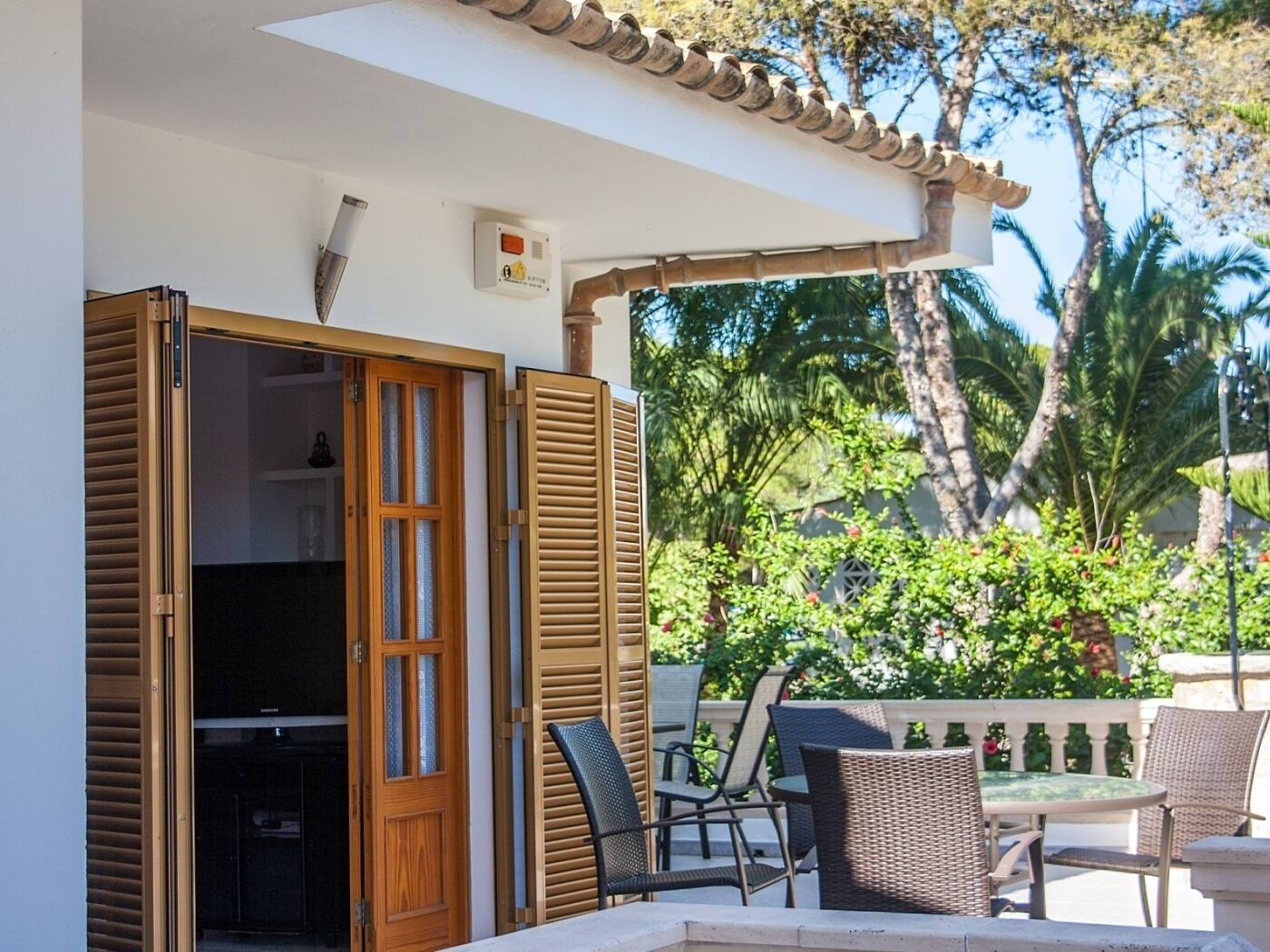 Une terrasse extérieure avec une table et des chaises, une porte en bois et une vue sur la verdure et les arbres.