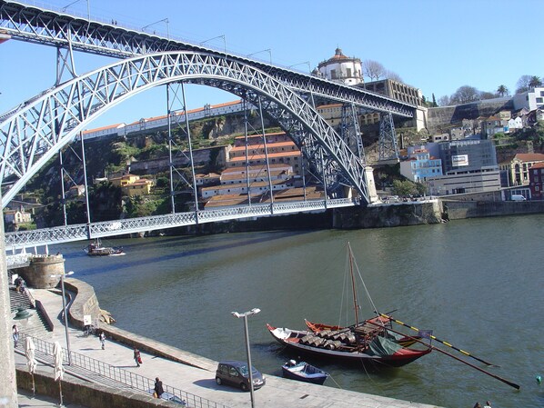 A large steel bridge spanning a river with a town and buildings in the background.