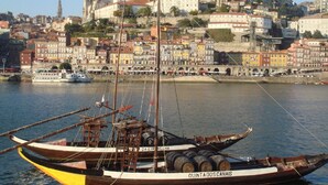 A traditional boat docked at a harbor with a historic building in the background.