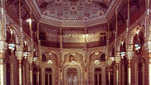 An ornate interior with intricate architectural details, including arches and columns, and a patterned ceiling.