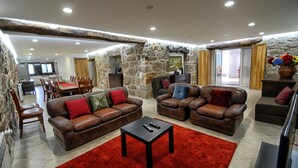 Un vaste espace de vie avec des murs en pierre, des canapés en cuir et un tapis rouge.