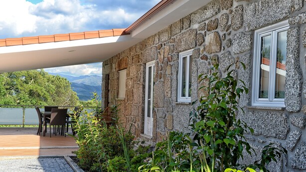 Un bâtiment en pierre doté d’un patio couvert, d’un espace extérieur aménagé pour s’asseoir et offrant une vue sur les montagnes.