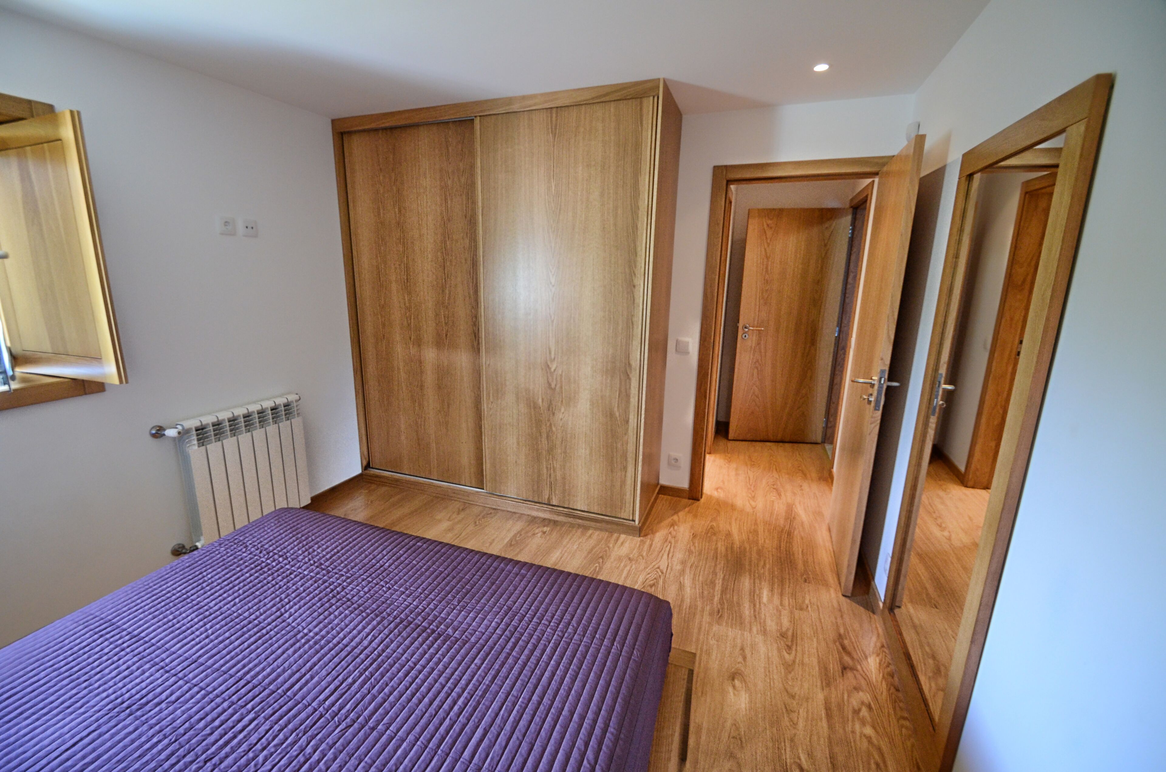Ein Schlafzimmer mit Bett, Kleiderschrank und einer Tür zu einem anderen Raum.