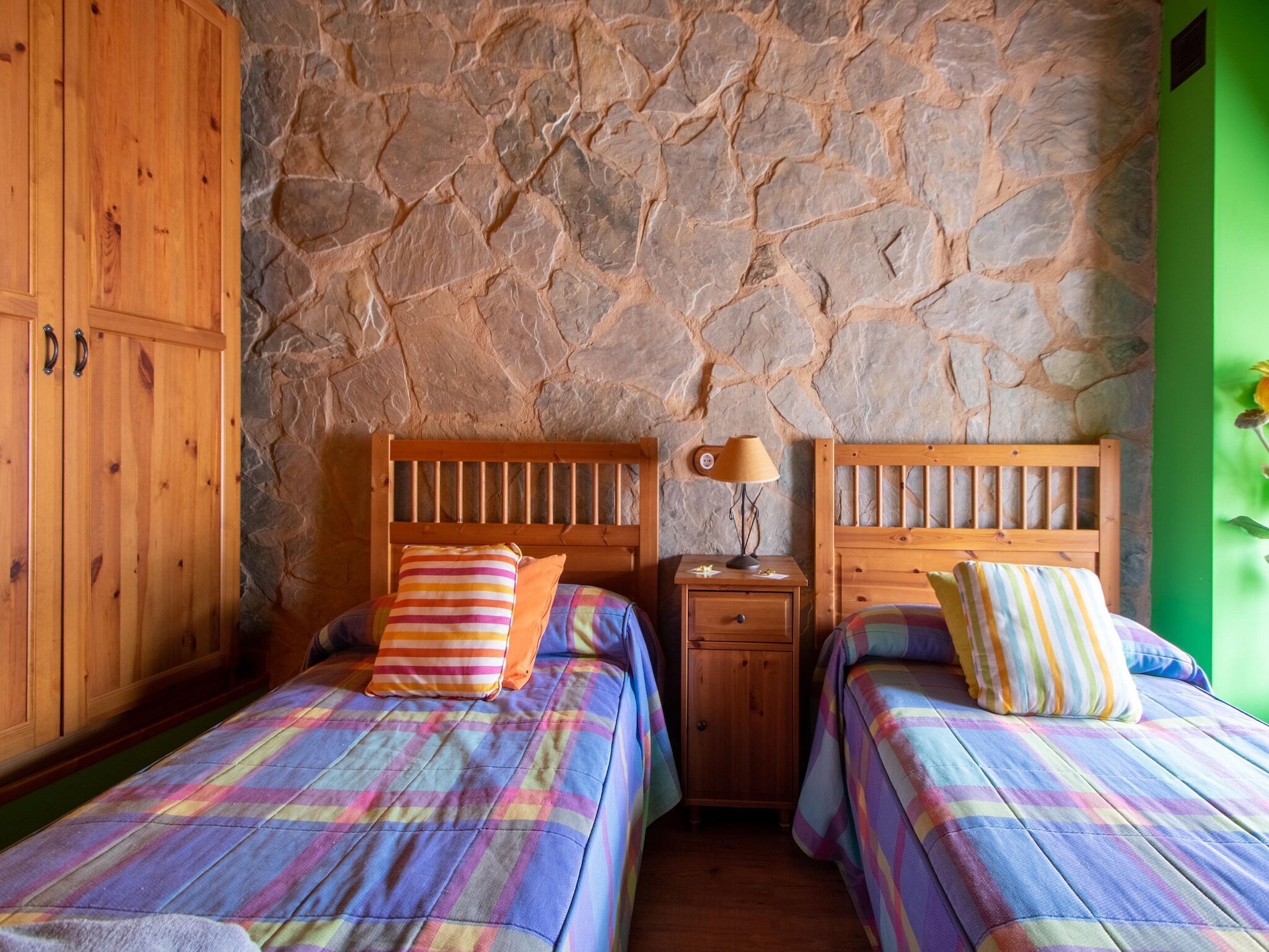 Een kamer met twee houten bedden, een stenen muur en een groene wand.