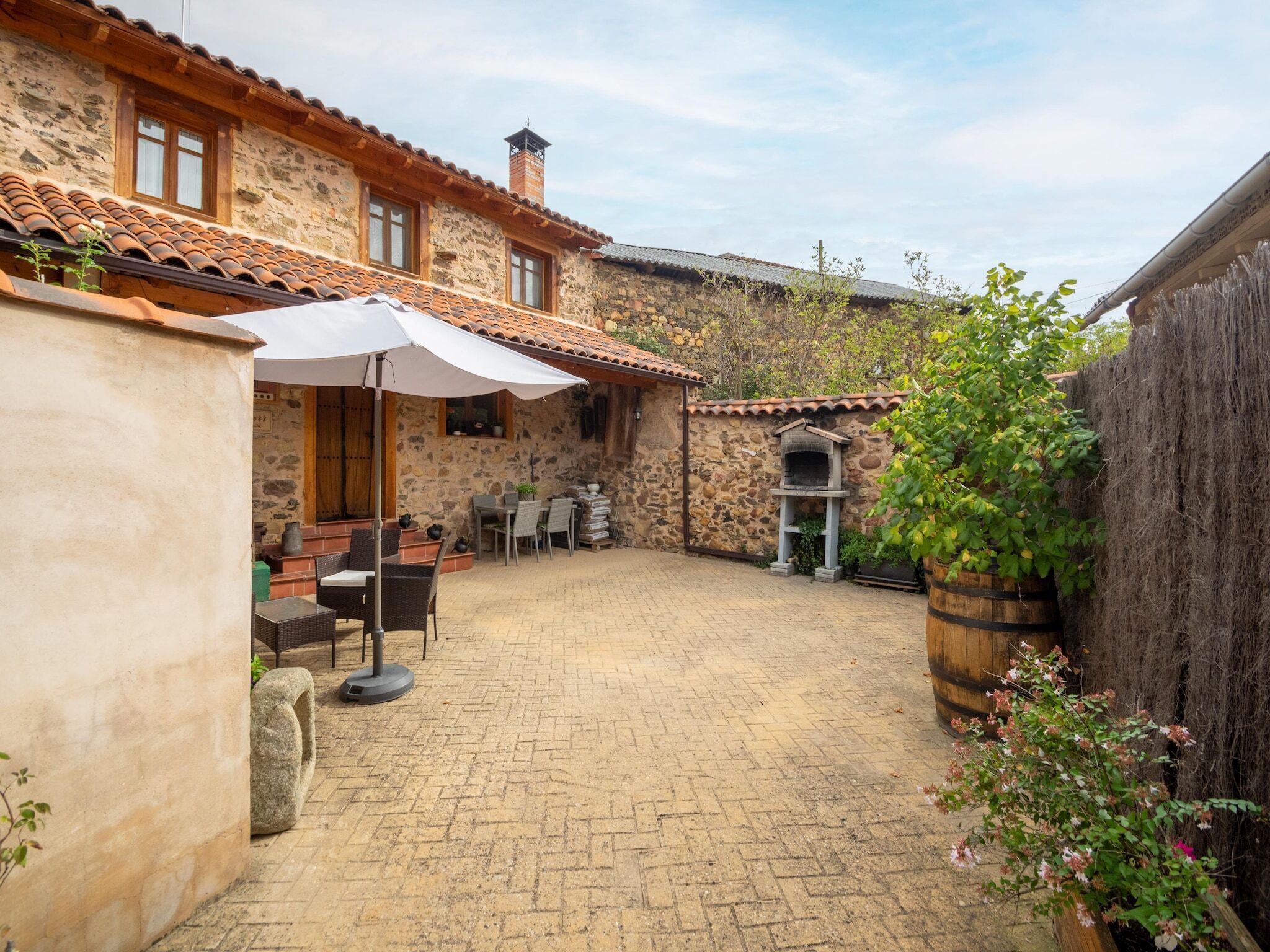 A stone building with a tiled roof, outdoor seating, and a brick patio.