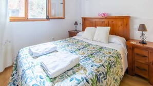 A bedroom with a bed, a wooden headboard, a nightstand with a lamp, a mirror, and three framed pictures on the wall. - Romantic Escape with Terrace (La Omañuela, León)
