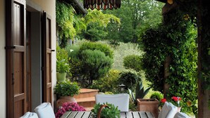 An outdoor patio with a wooden table and chairs, surrounded by lush greenery and potted plants. - Luxury Private Villa with 15mx6m Pool. Private Setting with Panoramic views (orturano, bagnone)