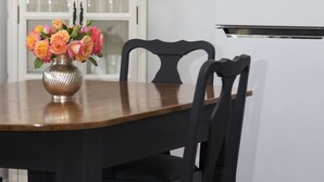 A dining table with a vase of flowers, black chairs, and a white cabinet in the background. - Country Mile Escape (Flying Fox)