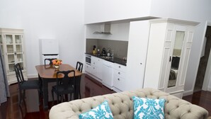 A compact living space with a dining area, kitchenette, and a sofa with patterned cushions. - Country Mile Escape (Flying Fox)