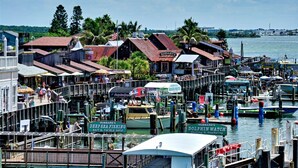 Un área de muelle frente al agua con varios barcos, una tienda de aparejos de pesca y un restaurante llamado 'Scullery's'.