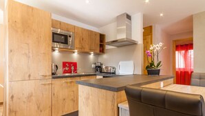 Een moderne keuken met houten kastjes, een ingebouwde magnetron en een centraal kookeiland met zitplaatsen.