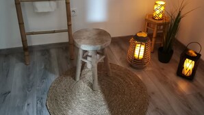 Una habitación con una escalera de madera, un taburete pequeño, un tapiz tejido y tres faroles encendidos.