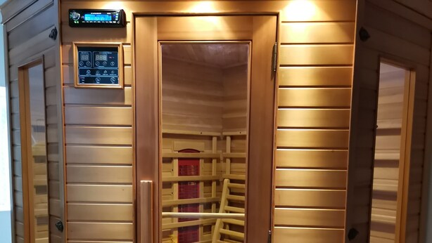Una sauna con paredes de madera, un panel de control y un banco en su interior.