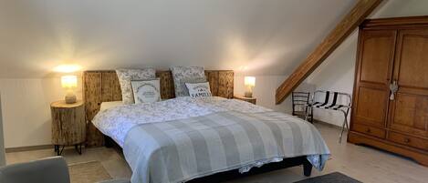 A bedroom with a bed, two bedside tables with lamps, a wardrobe, and a chair.