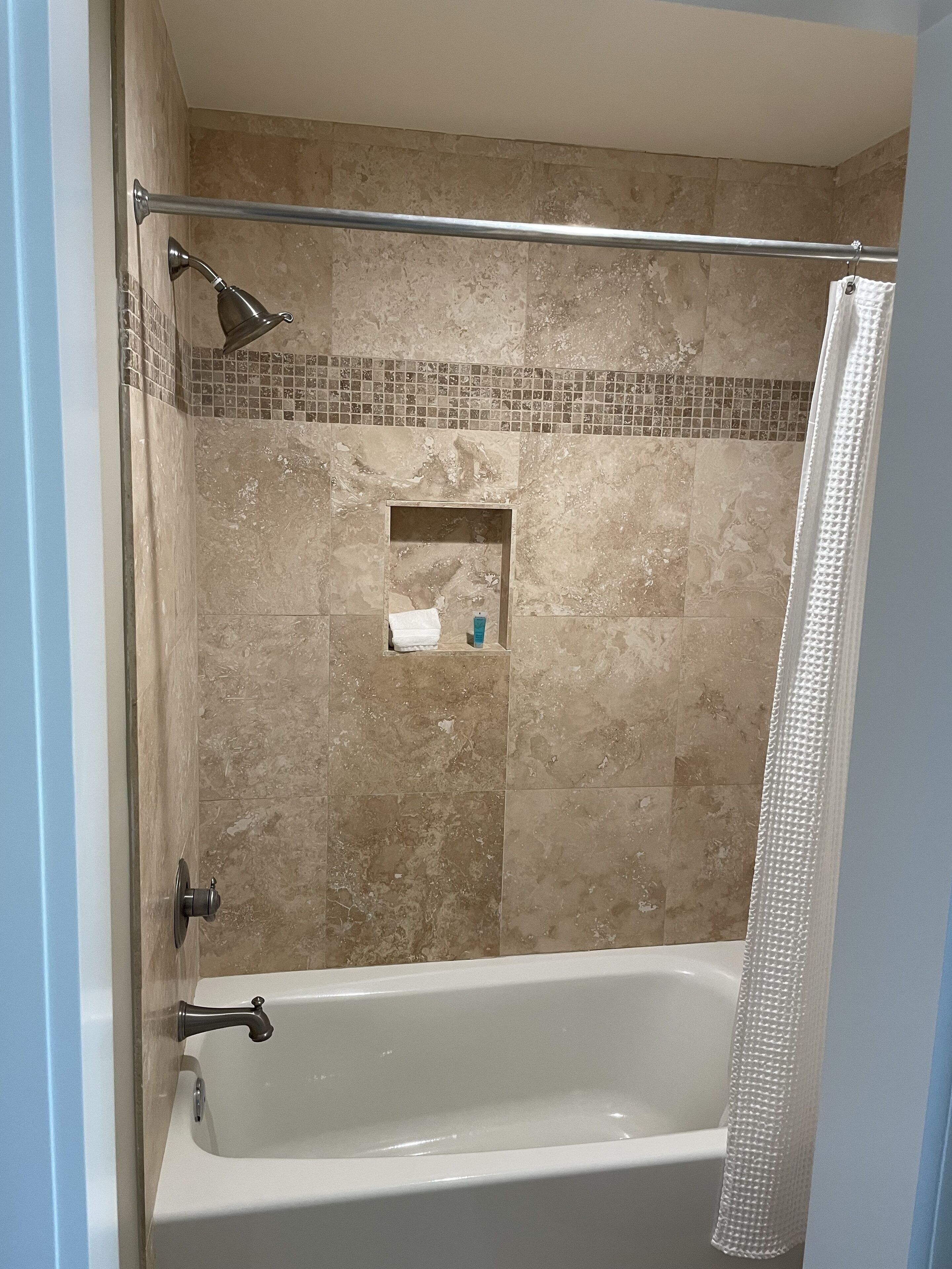 A bathroom with a bathtub, shower curtain, and tiled walls.