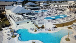A resort with multiple swimming pools, covered areas, and a variety of seating arrangements. - Steps away from Camp Watercolor Amenities  (Santa Rosa Beach)