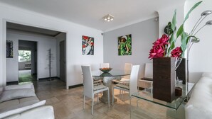 Un comedor moderno con una mesa de cristal, sillas blancas y obras de arte en las paredes.