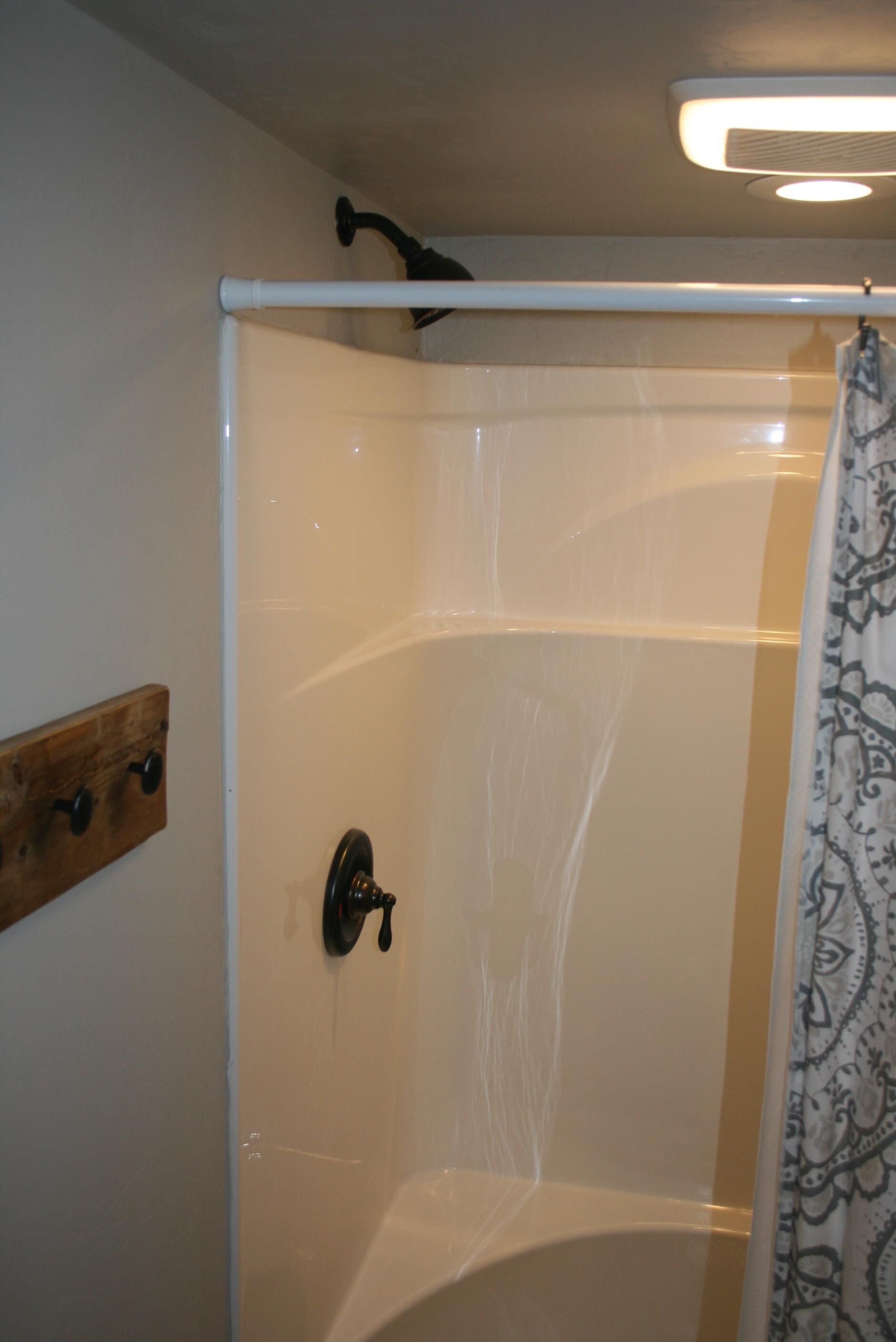 Un espace douche doté d’une porte en verre, d’un porte-serviettes en bois et d’un rideau de douche à motifs.