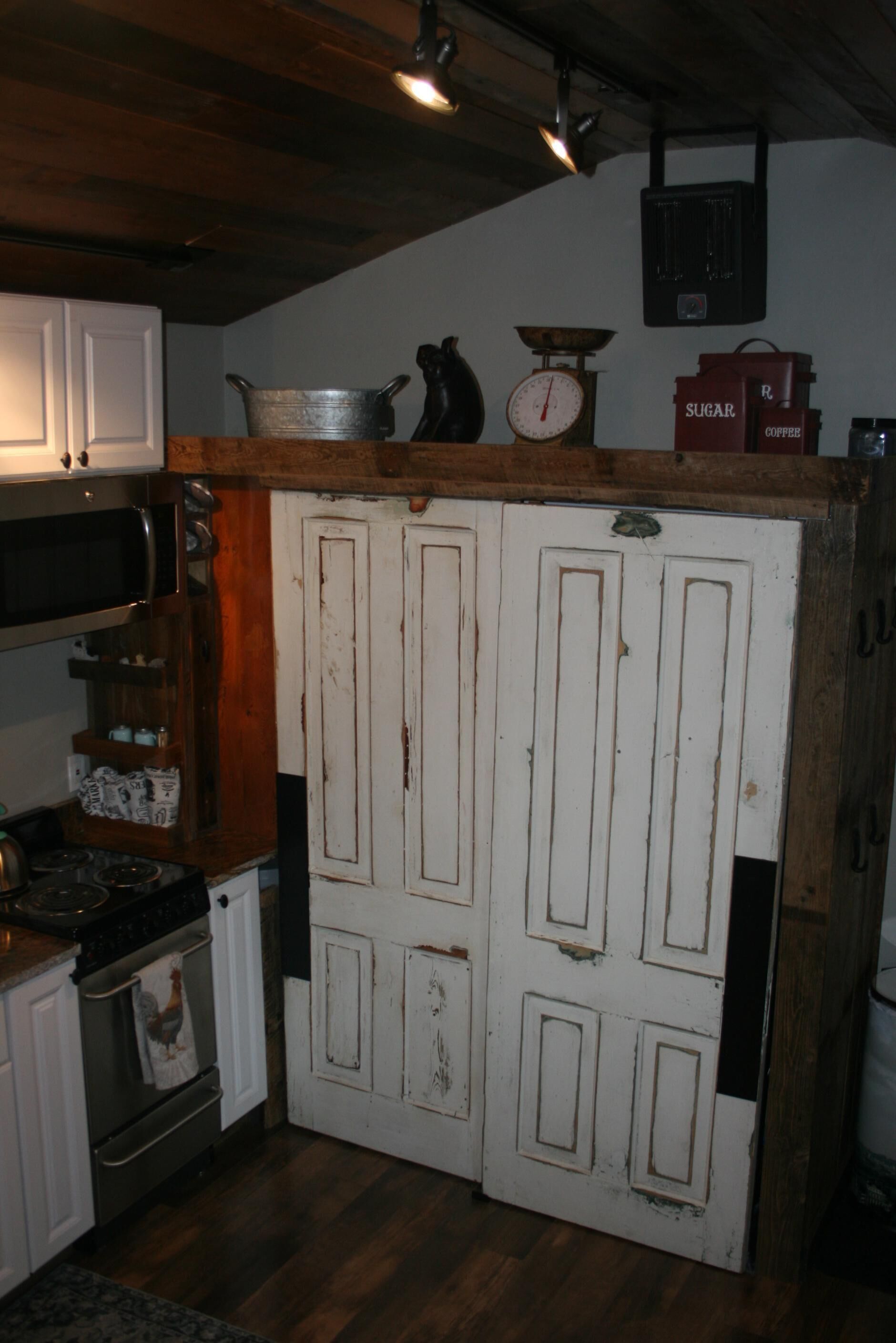 Een landelijke keuken met houten kastjes, een fornuis en een witte deur met een weegschaal erboven.