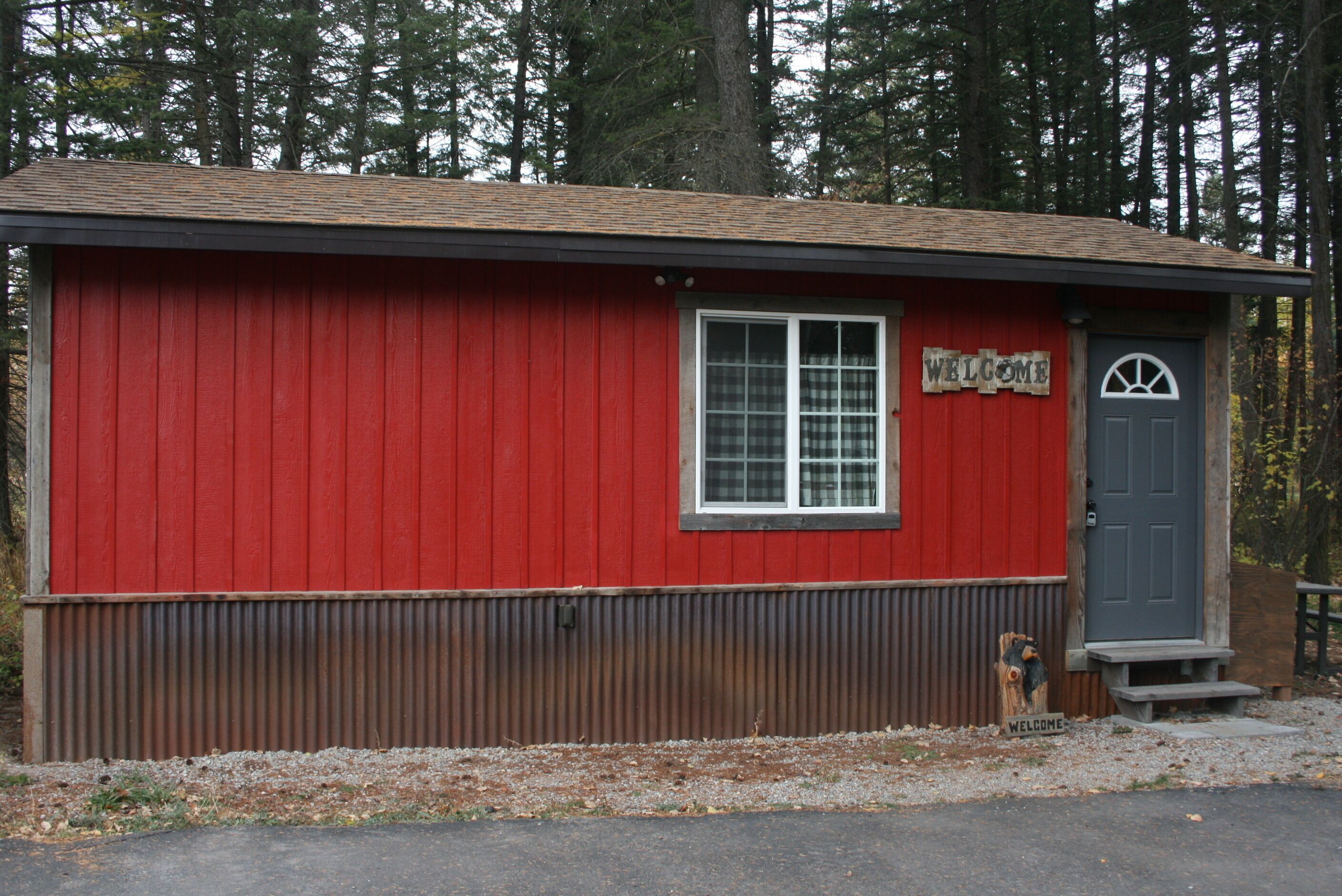 A red building with a 'WELCOME' sign, a window, and a door.