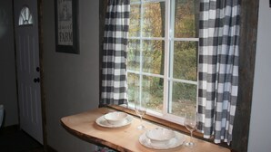 A kitchen with a window, a wooden table, and two white plates with a wine glass. - Tiny Red Farmhouse centrally located in Columbia Falls (Columbia Falls)