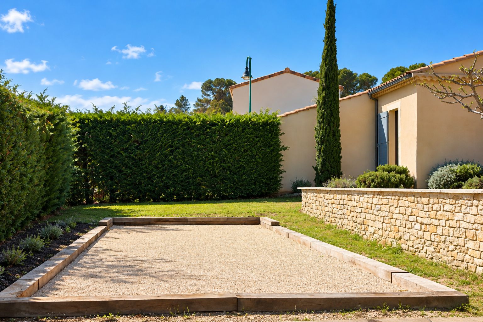 A courtyard with a gravel path, a stone wall, and a neatly trimmed hedge.