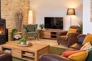 Un salon chaleureux avec une cheminée, un téléviseur et des fauteuils confortables.