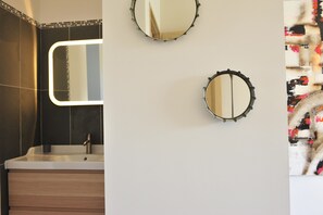 Un baño con diseño moderno, que incluye un espejo grande, un lavamanos y un adorno en la pared.
