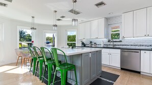 A modern kitchen with white cabinets, a central island, and green bar stools. - Waterfront Estate Exclusive-Paradise Lighthouse Point Florida Private Pool/Spa (Lighthouse Point)