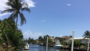 A wooden dock with turquoise chairs, a boat, and a calm river. - Waterfront Estate Exclusive-Paradise Lighthouse Point Florida Private Pool/Spa (Lighthouse Point)