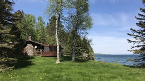 Une cabane avec une façade en pierre, une terrasse en bois et une vue sur un lac.