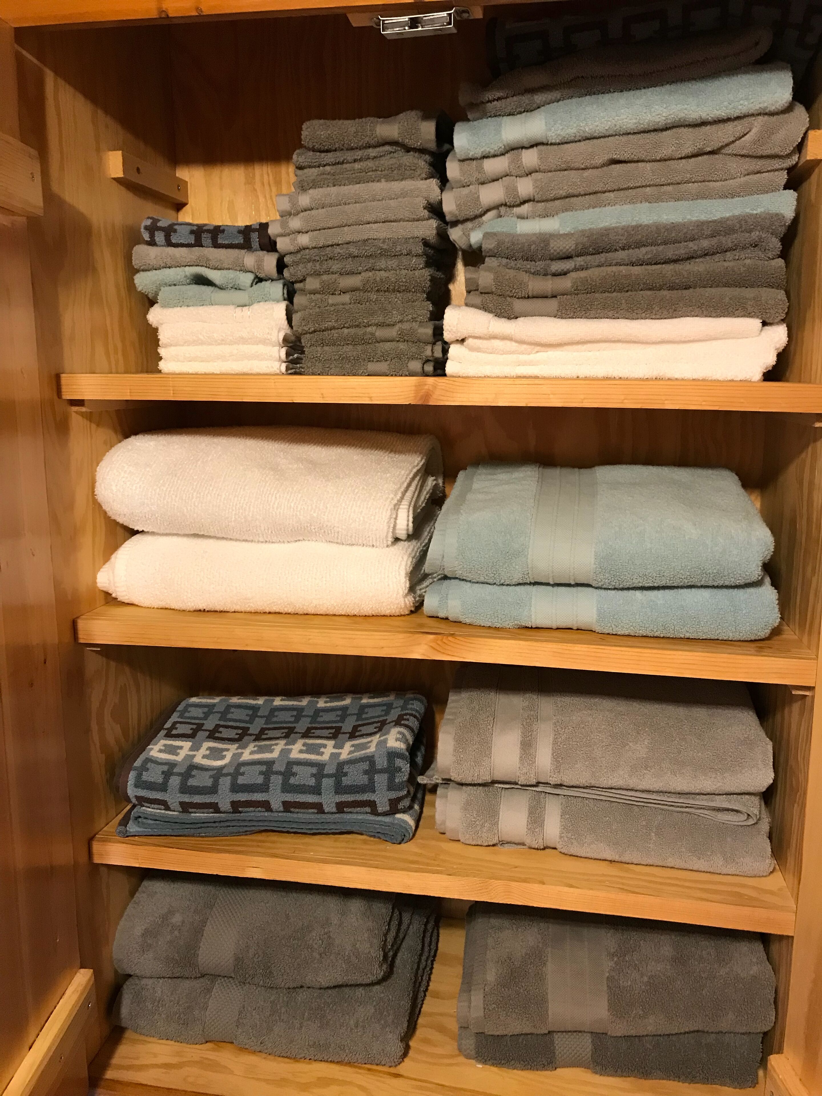 A wooden shelf with neatly folded towels in various colors and patterns.