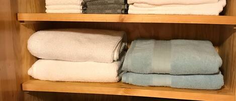 A wooden shelf with neatly folded towels in various colors and patterns.