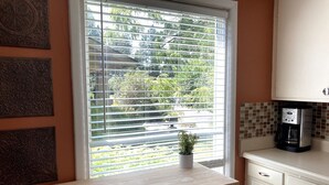 A kitchen with a window, a coffee maker, and a potted plant on the windowsill.
