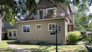 A two-story house with a balcony, a street sign, and a well-maintained lawn.