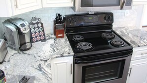 A kitchen with a stove, microwave, toaster, and knife block.