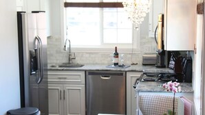 A modern kitchen with stainless steel appliances, a dishwasher, and a dining area with a table and chairs.