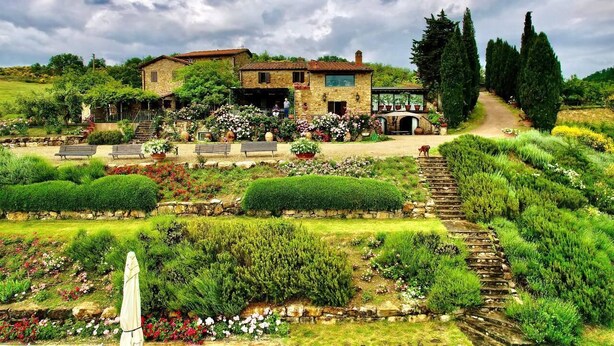 Una casa de piedra con jardín, un camino empedrado y una estatua.