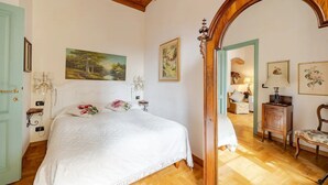 Un dormitorio con una cama grande, vigas de madera en el techo, una puerta de madera y un espejo.