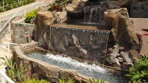 A hotel with a sign reading "Grande Bay Resort" and a waterfall feature in front of the building.