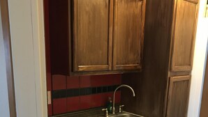Une cuisine avec des meubles en bois, un évier en acier inoxydable et un crédence rouge.