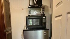 Une cuisine compacte équipée d’un réfrigérateur en acier inoxydable, d’un four à micro-ondes et d’une machine à café placés sur le plan de travail.